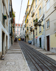 narrow steep street in lisbon with cable car
