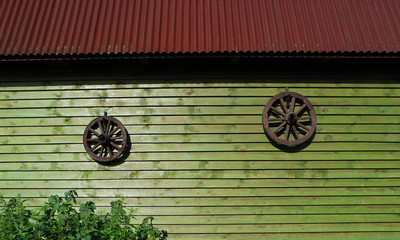 Two ancient wooden wheels on wall of wooden house