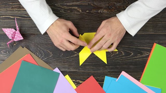 Man folding origami figure, top view. How to make origami fast. Easy origami butterfly.