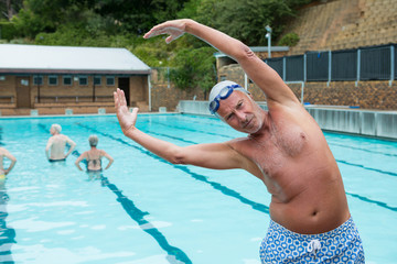 Smiling senior man excerising at poolside