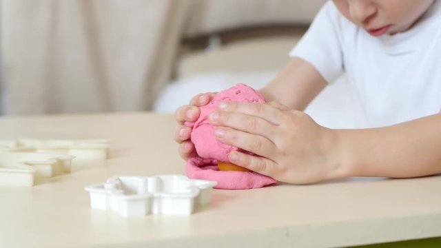 Children's creativity. The child's hands close-up form the figures from the color test on the table. Cute children's plasticine figurines on the table.