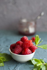 plate with raspberry and mint leaves and a jar of jam