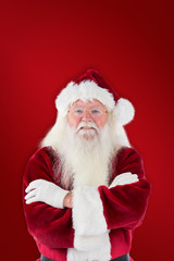 Santa smiles with folded arms against red background
