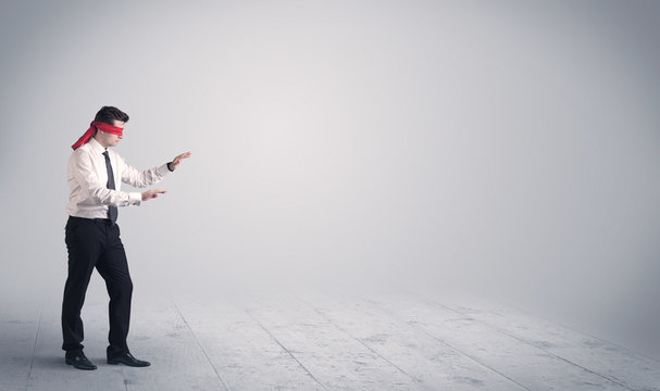 A young male business person in elegant dress standing with red blindfolds in a clear, empty space concept.