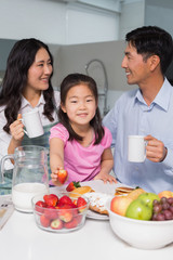 Portrait of a young girl enjoying breakfast with parents