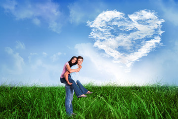 Young man giving girlfriend a piggyback ride against cloud heart