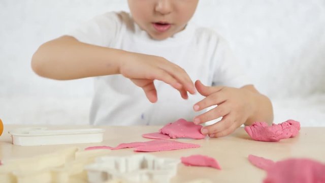 Children's creativity. The little boy forms the figures from the color test on the table. Cute children's plasticine figures on the table.