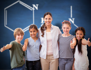 Cute pupils and teacher smiling at camera in computer class  against blue chalkboard