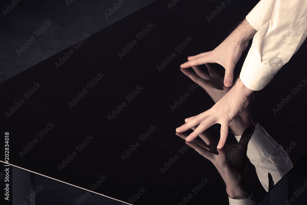 Poster Close up of a hand touching smart table with copy space on black background