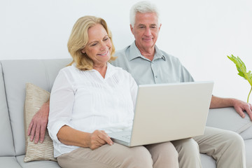 Relaxed senior couple using laptop at house