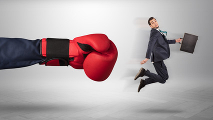 Giant hand gives a kick to a small employee businessman