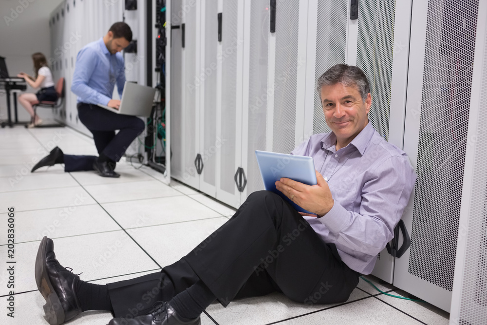 Poster Smiling technician working on digital tablet on the floor