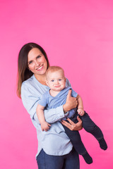 happy young mother with a baby child on pink background