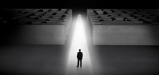 Businessman going straight ahead on a lighted carpet arrow between two maze
