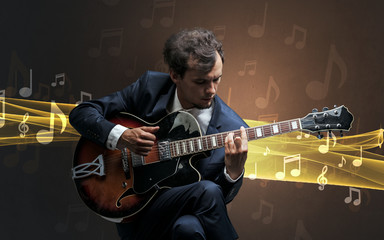 Obraz premium Young male musician playing on his guitar with musical notes around