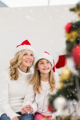 Festive mother and daughter smiling at tree against twinkling stars
