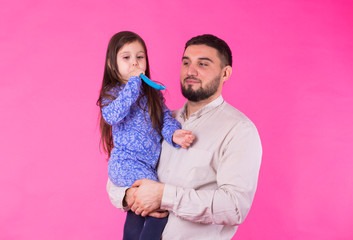 Happy father with his baby daughter on pink background