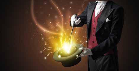 Magician hand conjure with wand  light from a black cylinder