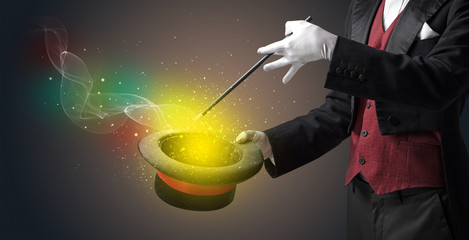 Illusionist hand starts to conjure with white glove and magic wand