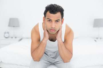 Portrait of a serious man sitting on bed