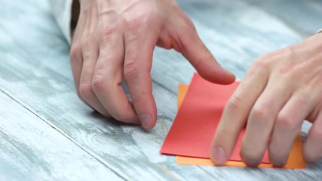 Man creating origami close up. Male hands dividing paper sheet in half. Paper folding lesson.