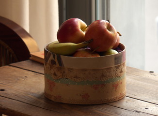 Still life of fruits in a wooden box in front of a window