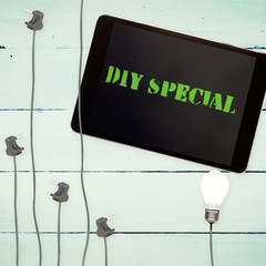 The word diy special against bulbs and tablet on wooden background