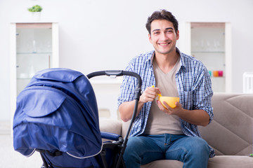 Young father looking after newborn baby at home