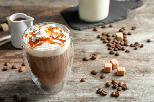Glass of coffee with caramel topping on wooden background