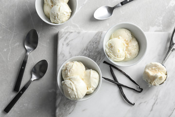Bowls with tasty vanilla ice cream on marble board