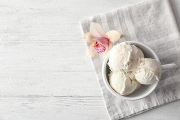 Obraz na płótnie Canvas Cup with tasty vanilla ice cream on wooden background, top view