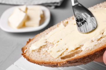 Spreading tasty butter on slice of fresh bread, closeup