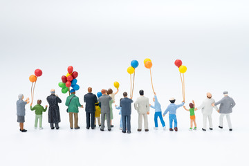 Back view of miniature people happy family, audiences, spectators holding balloons watching the...