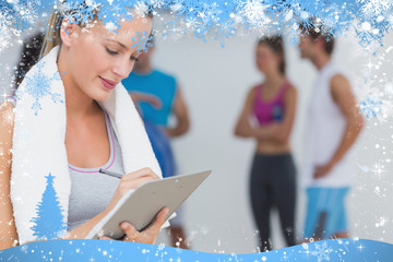 Trainer writing on clipboard with fitness class in background at gym against snow