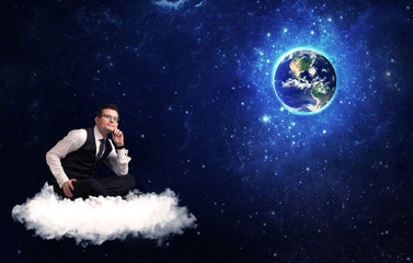 Fototapeta na wymiar Caucasian businessman sitting on a white fluffy cloud looking and wondering at planet earth