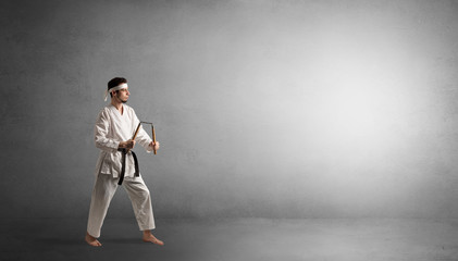 Fototapeta na wymiar Small karate man fighting in an empty grey copy space