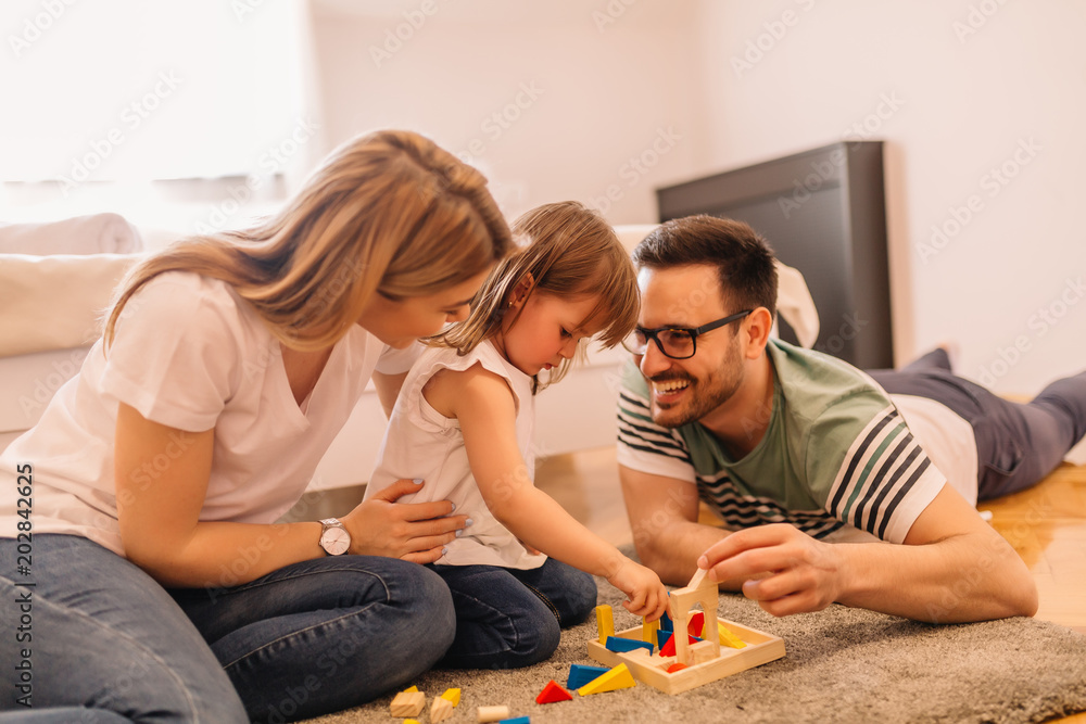 Wall mural Happy family is having fun while they are solving puzzles on the floor in bedroom