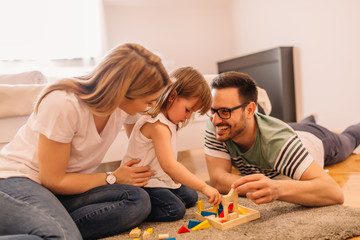Happy family is having fun while they are solving puzzles on the floor in bedroom