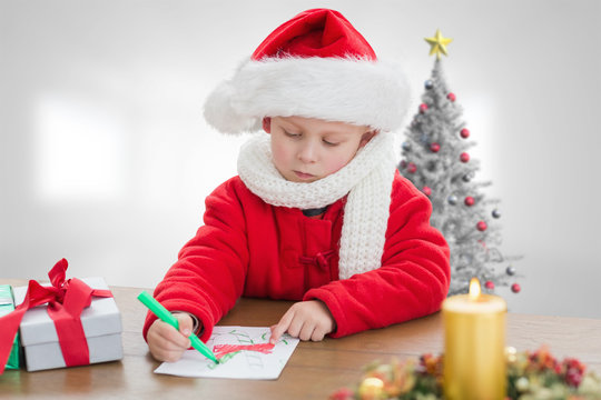 Cute boy drawing festive pictures  against christmas tree in bright room