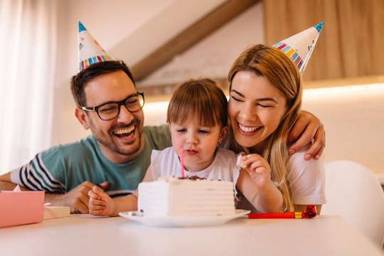 Happy parents are wearing birthday caps while they are celebrating daughters birthday in their home