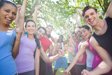 Fitness group cheering at camera in park