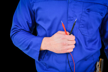 Electrician holding multimeter against black