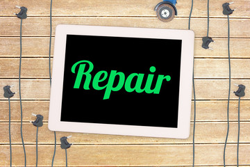 The word repair against plug and tablet on wooden background