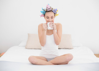 Obraz na płótnie Canvas Calm natural brown haired woman in hair curlers enjoying coffee smell