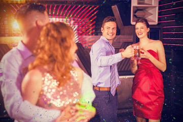 Couple interacting with friends while dancing against flying colours