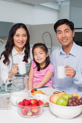 Portrait of a happy young girl enjoying breakfast with parents
