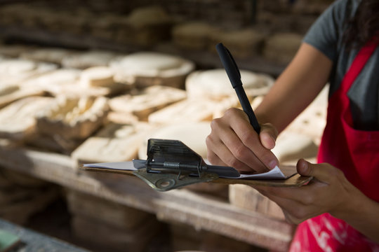Female potter writing in clipboard