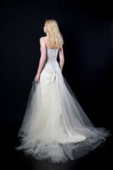 full length portrait of woman wearing white bridal gown. standing poison black studio background.