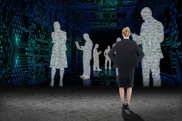Businesswoman standing with hands on hips against business people in data matrix