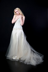 full length portrait of woman wearing white bridal gown. standing poison black studio background.